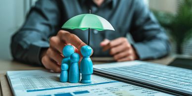 Figures protected under a green umbrella on financial documents.