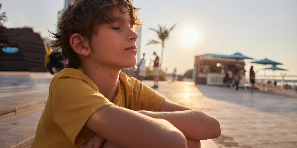 Boy in yellow shirt enjoying a sunset outside.
