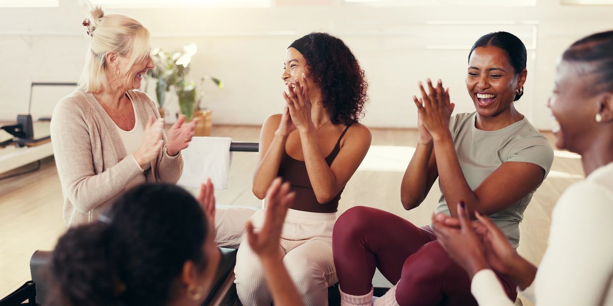 Group of women clapping and smiling indoors.