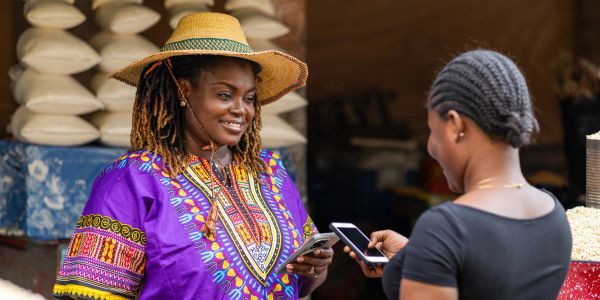 Two women using smartphones in an outdoor market.