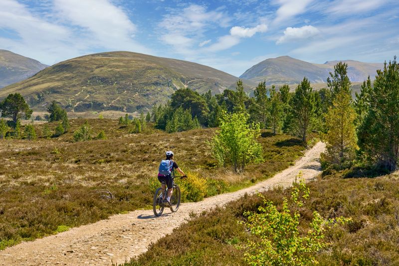 nice senior woman riding her electric mountain bike in the highlands of Cairn Gorms National Park , Scotland, UK
