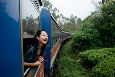 Woman smiling and looking out of a train window.