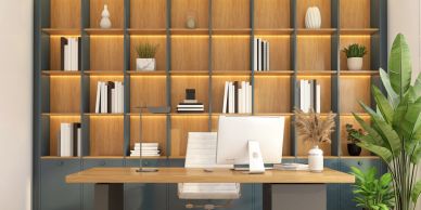 Modern office desk with computer and illuminated wooden bookshelf.