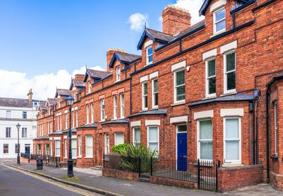 Row of classic red brick townhouses with blue doors on a quiet street.