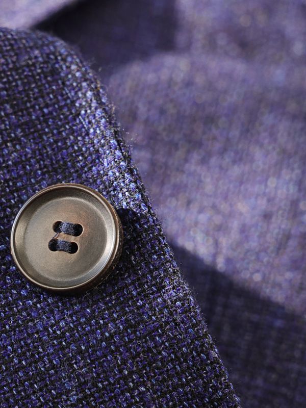 Close-up of a button on textured purple fabric.