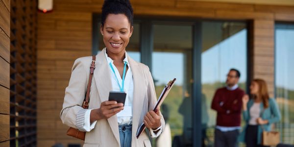 Smiling businesswoman checking her phone outside an office.