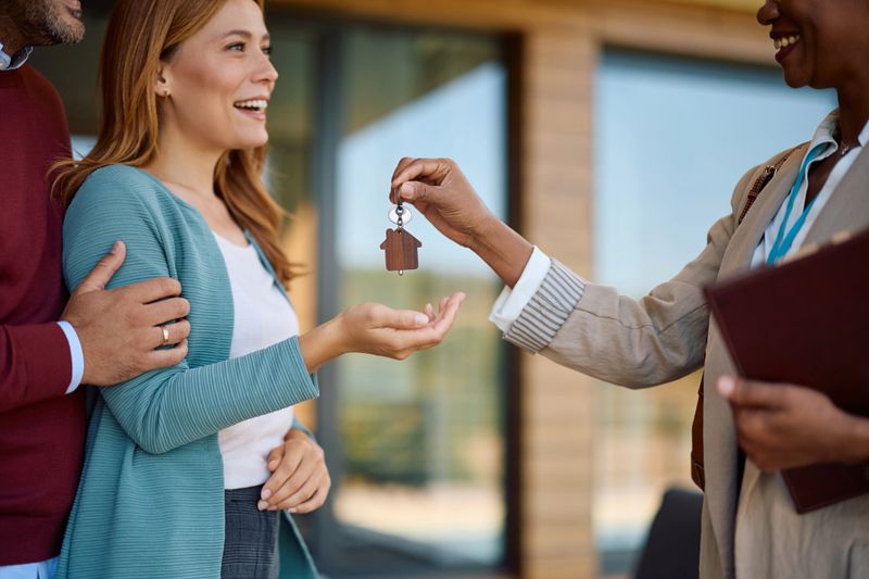 Close up of real estate agent giving keys of a new house to her buyers.