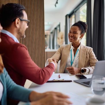 Two professionals shaking hands during a meeting in an office.