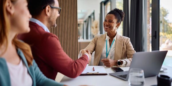 Two people shaking hands with a woman in an office setting.