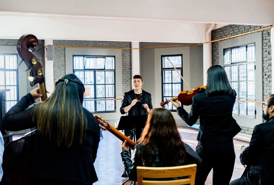 Four musicians dressed formally holding string instruments and posing.