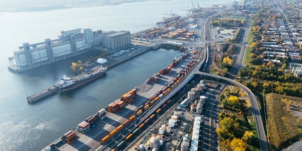 Aerial view of a busy port with cargo containers and ships near a city.