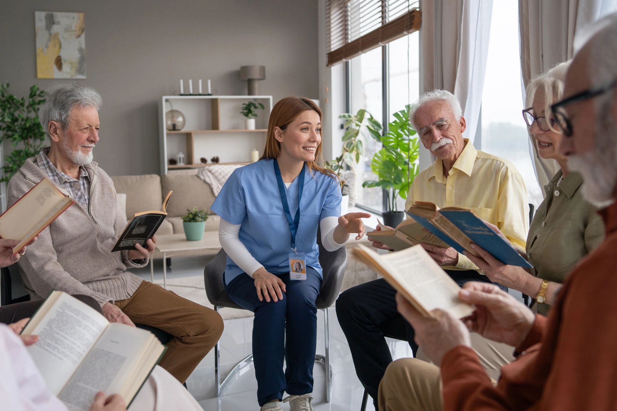 Nurse leading a book reading session with elderly people in a cozy room.