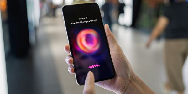 Person using voice assistant on smartphone in a public space.