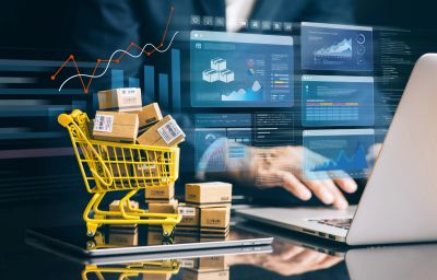 Shopping cart with boxes and business data on a laptop.