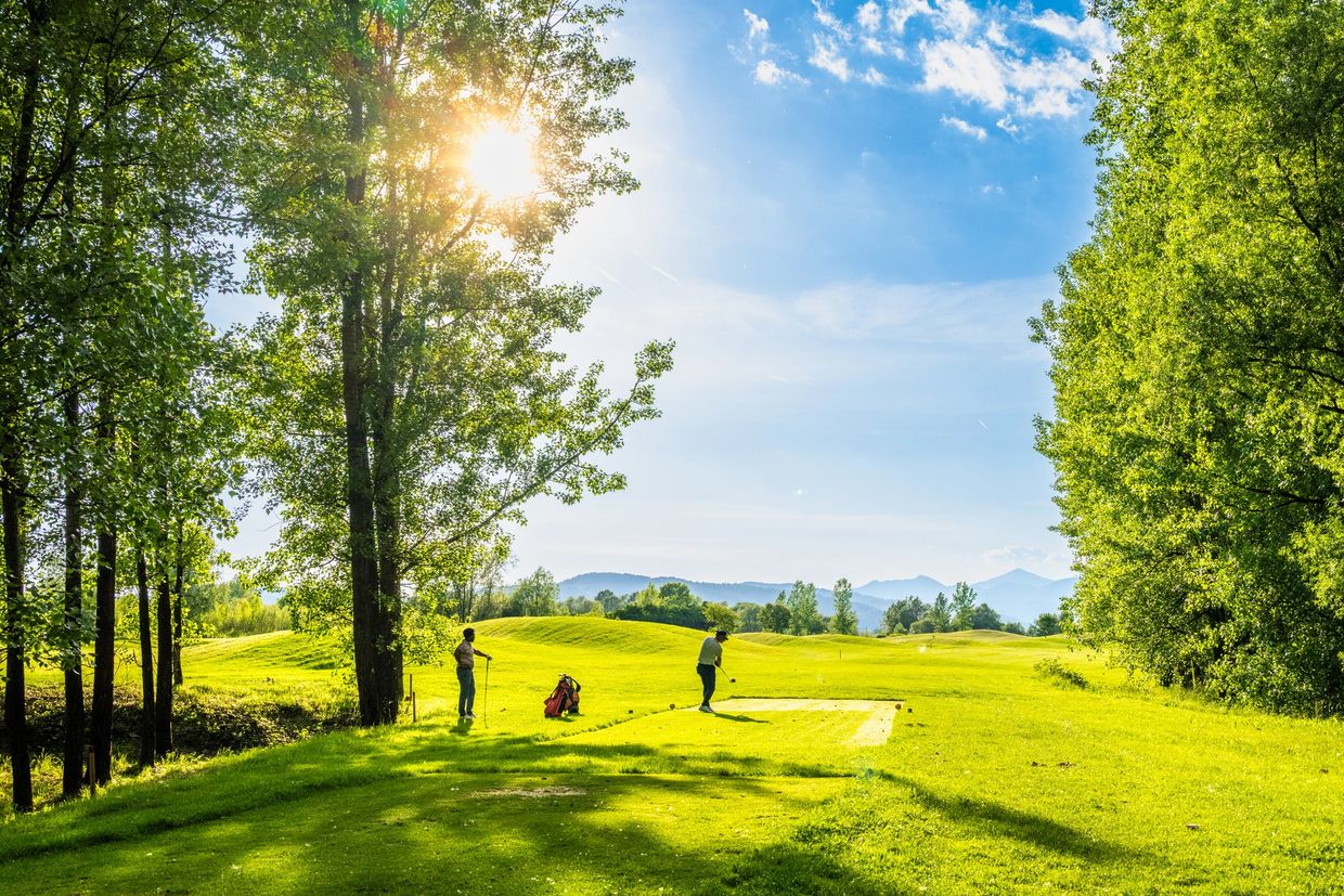 Two people playing golf on a bright sunny day.