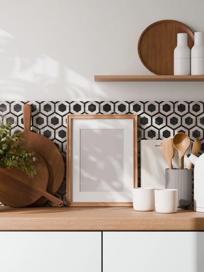 Modern kitchen counter with wooden utensils and a framed picture.