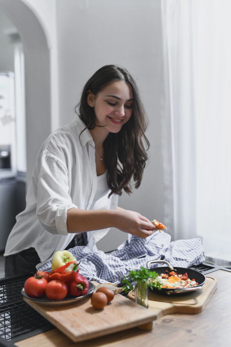 Cheerful Woman Tasting Freshly Made Shakshouka With Joyful Expression