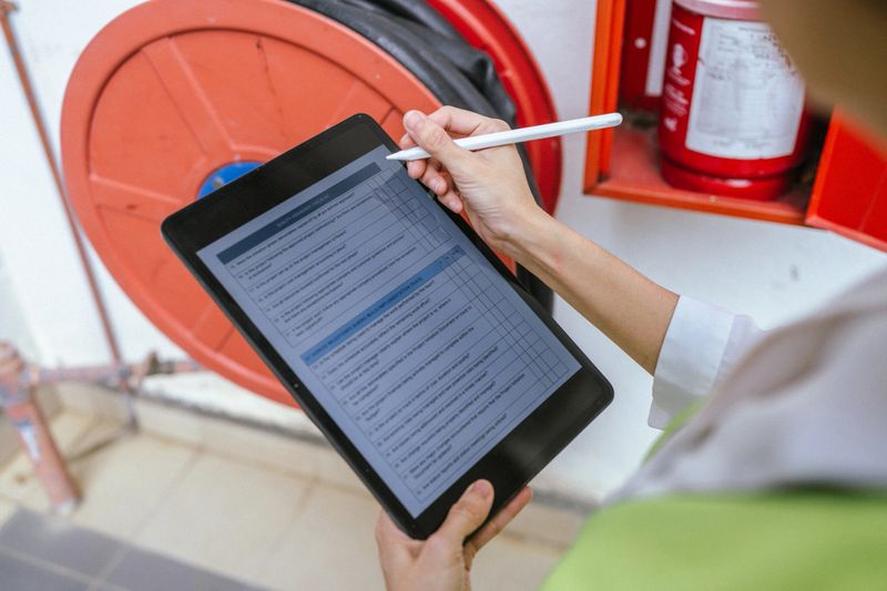 An Asian female building inspector using a digital tablet checking a fire hose cabinet