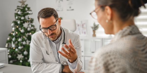 Doctor consulting a patient in a festive-decorated office.