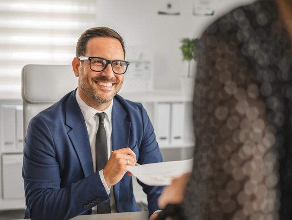 Smiling businessman in a suit reviewing documents during a meeting.