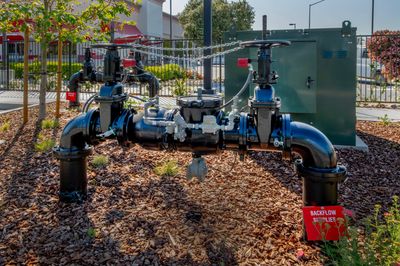Outdoor water pipes with valves and a red warning sign.