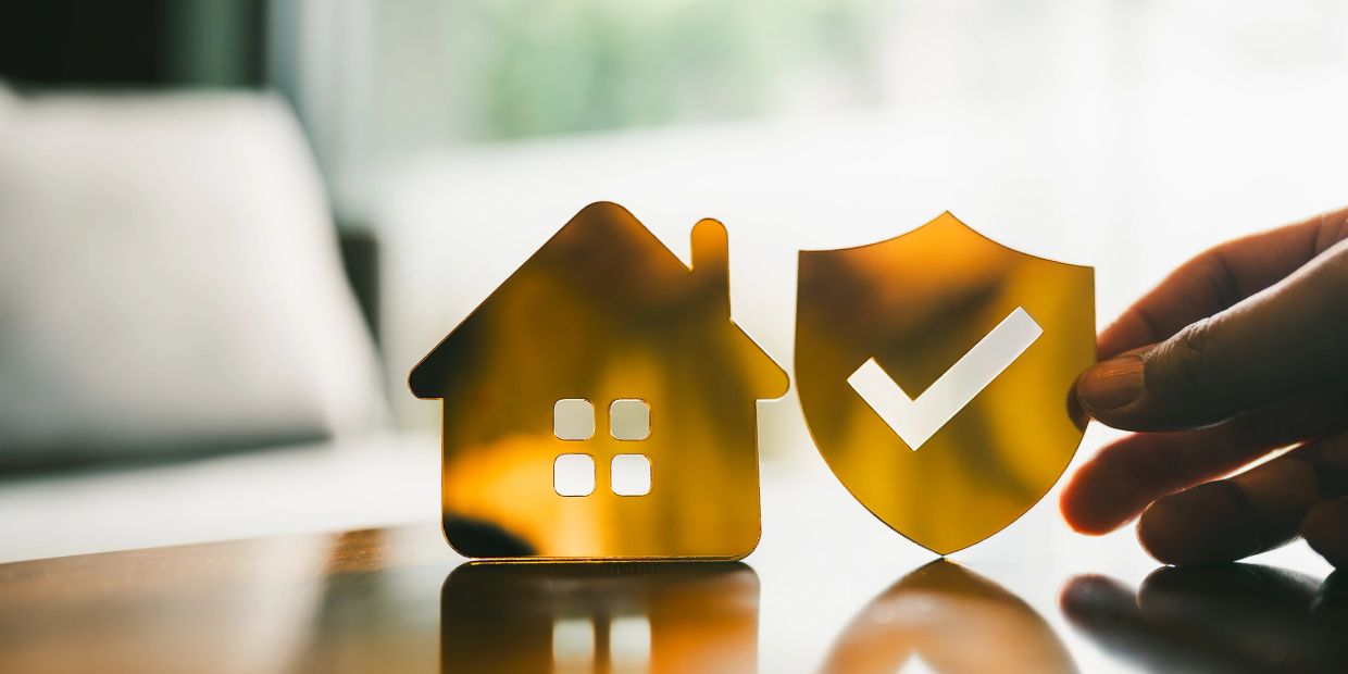 Golden house and shield icons symbolizing home protection and security.