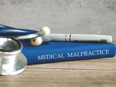 A stethoscope and pen on a medical malpractice book.