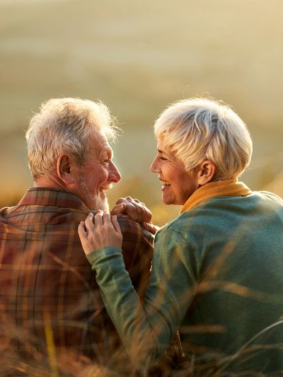 Elderly couple sharing a joyful moment outdoors during sunset.