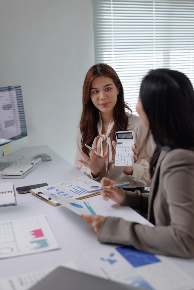 Two business colleagues collaborating on financial reports, analyzing charts and calculating numbers in a modern office meeting