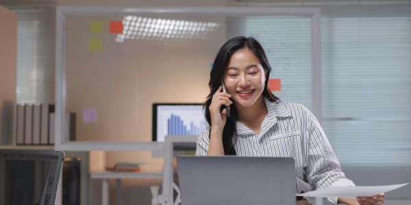 Woman multitasking with laptop and phone in the office.