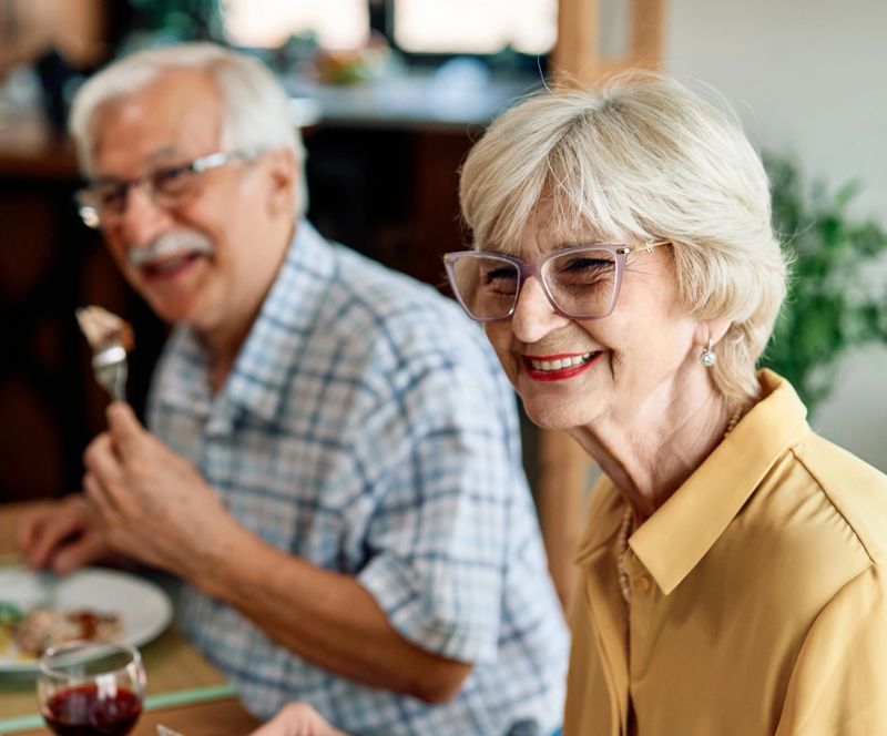 Happy multi-generation family gathering around dining table and having fun during a lunch or dinner on holiday or weekend, senior couple, grandparents, grandmother and grandfather eating