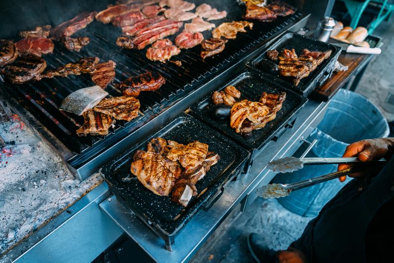 "Maestro de la Parrilla" Grillmaster Tending Meat over a Coal Fire at an Argentine Asado