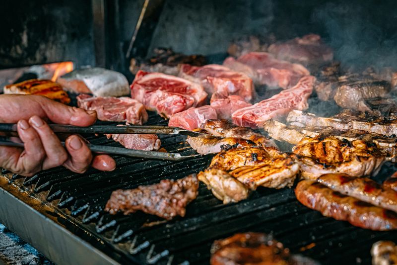 Man's Hand Grilling at an Argentine Asado over a Coal Fire