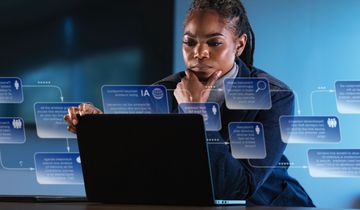 Focused woman working on laptop while people rush by in office.
