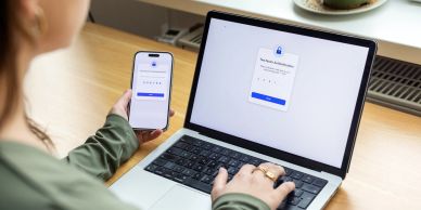 Person using phone and laptop for two-factor authentication.