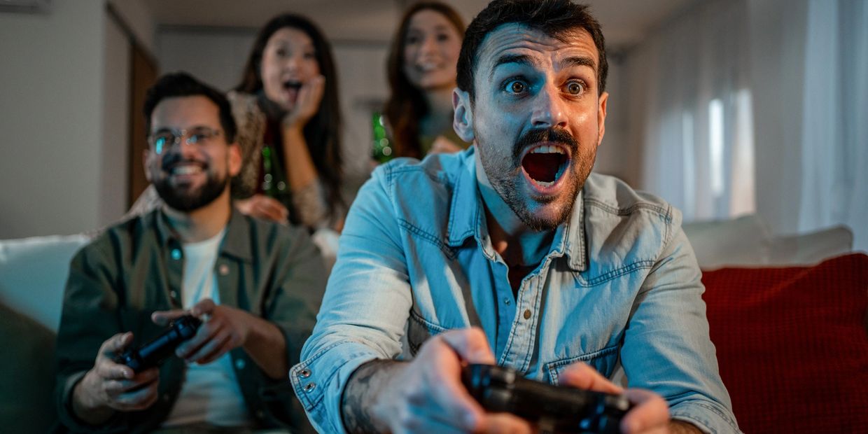 Group of friends excitedly playing video games together in a cozy living room.