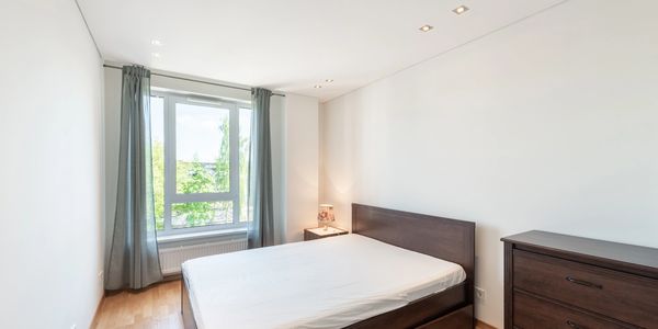 Minimalist bedroom with a large window and dark wood furniture.