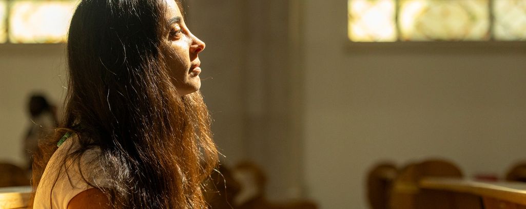A priest giving confession with Jesus present and light rays connecting them.
