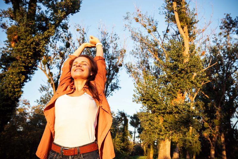Smiling woman raising arms enjoying freedom outdoors