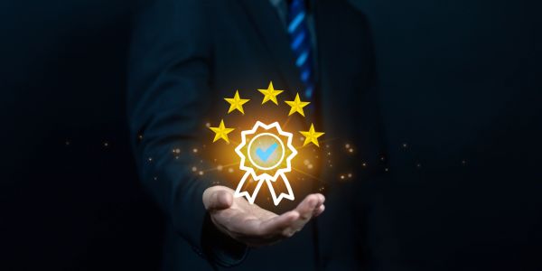 Hand presenting a glowing quality badge with five stars.