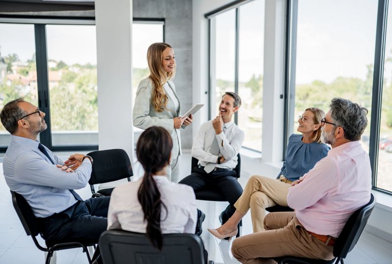 Businesswoman presenting to diverse group of professionals in a modern office, fostering discussion and collaboration