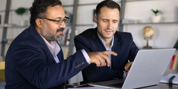 Two businessmen working together on a laptop.