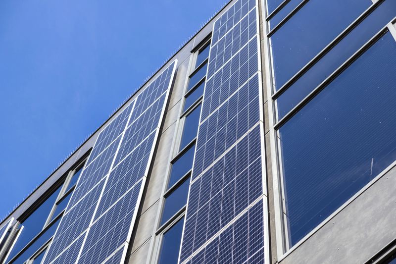 Contemporary architectural exterior showcasing numerous photovoltaic panels on its vertical surface, effectively capturing sunlight for eco-friendly power generation