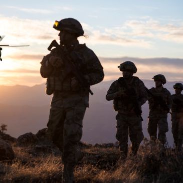 Silhouetted soldiers walking at sunset.