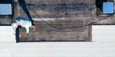Worker applying waterproofing on a flat roof.