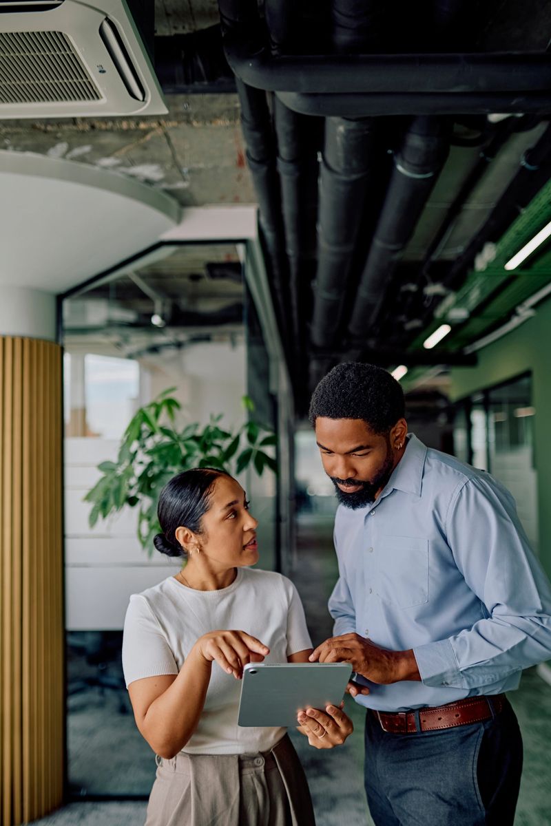 Diverse business colleagues discussing project details and sharing ideas, working together using a digital tablet in a contemporary office setting