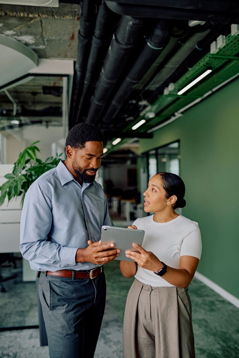 Multiracial business colleagues collaborating on a digital tablet, discussing ideas during a meeting in a contemporary workspace