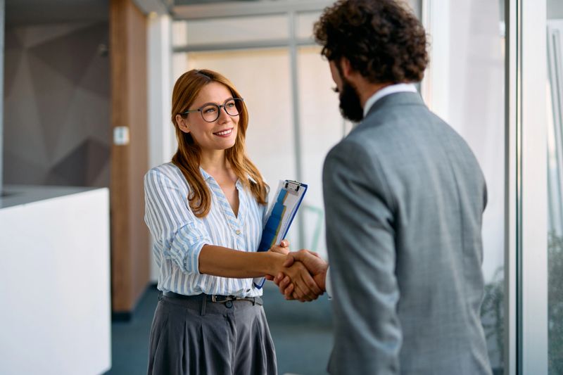 Businesswoman and businessman shaking hands, finalizing a deal in a modern office, celebrating a successful partnership and collaboration between colleagues