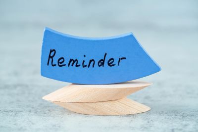 Blue note card with 'Reminder' written on it, held by wooden clips.