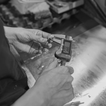 Person measuring a small metallic part with a digital caliper.